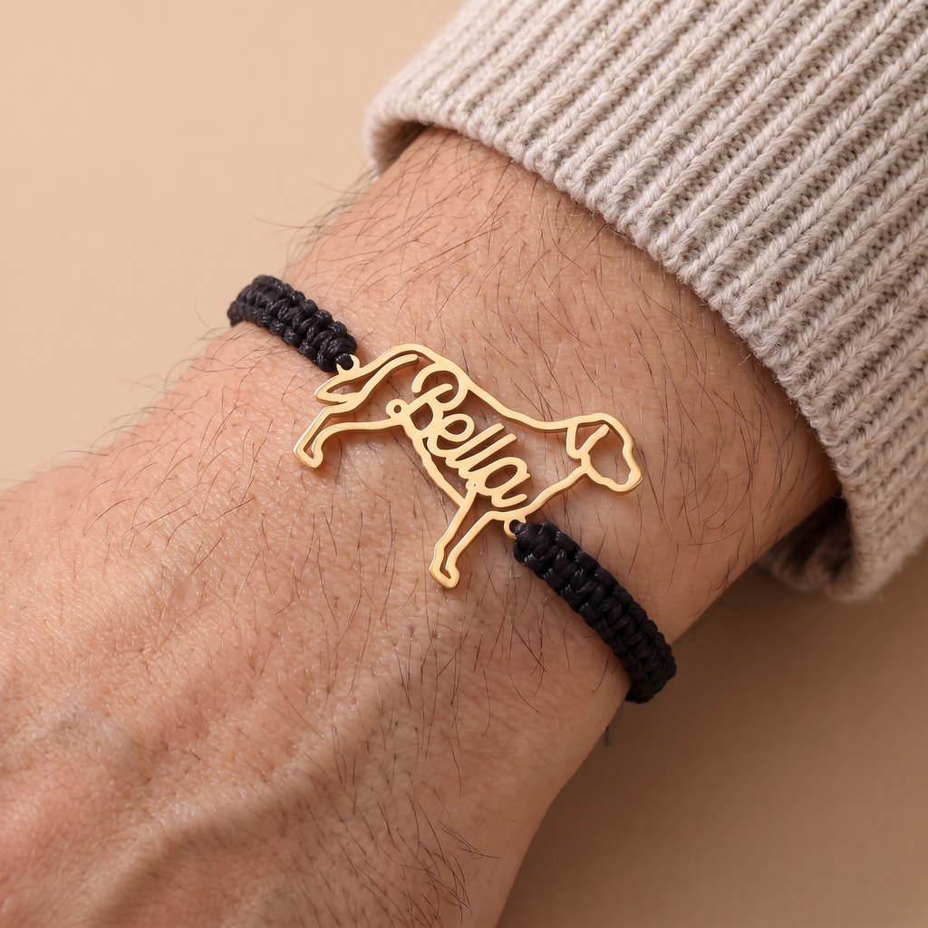 Gold pet name bracelet on a black braided cord, worn on a man's wrist
